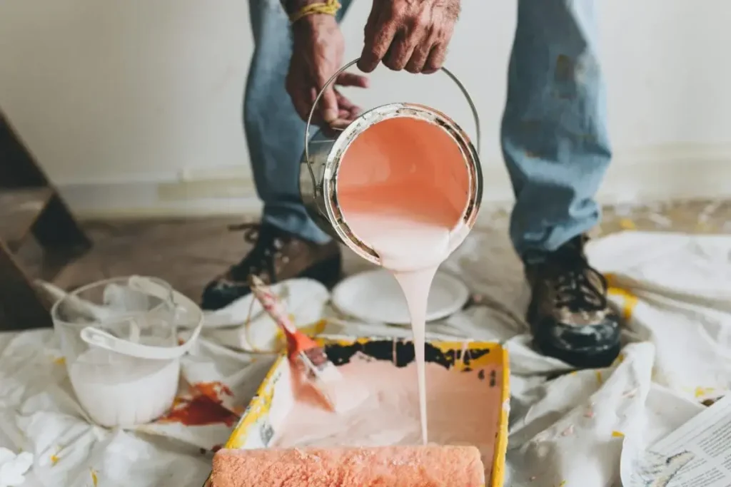 Pouring peach coloured paint into a paint tray.