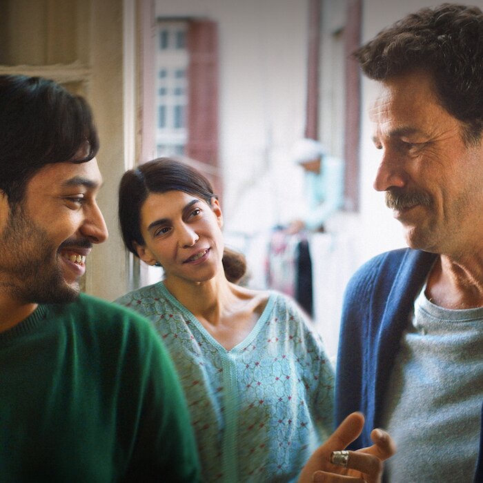Yhe Blue Caftan movie still, showing two men and a woman smiling.